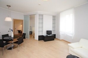 A modern living room with a dining area, a TV, and a white sofa.