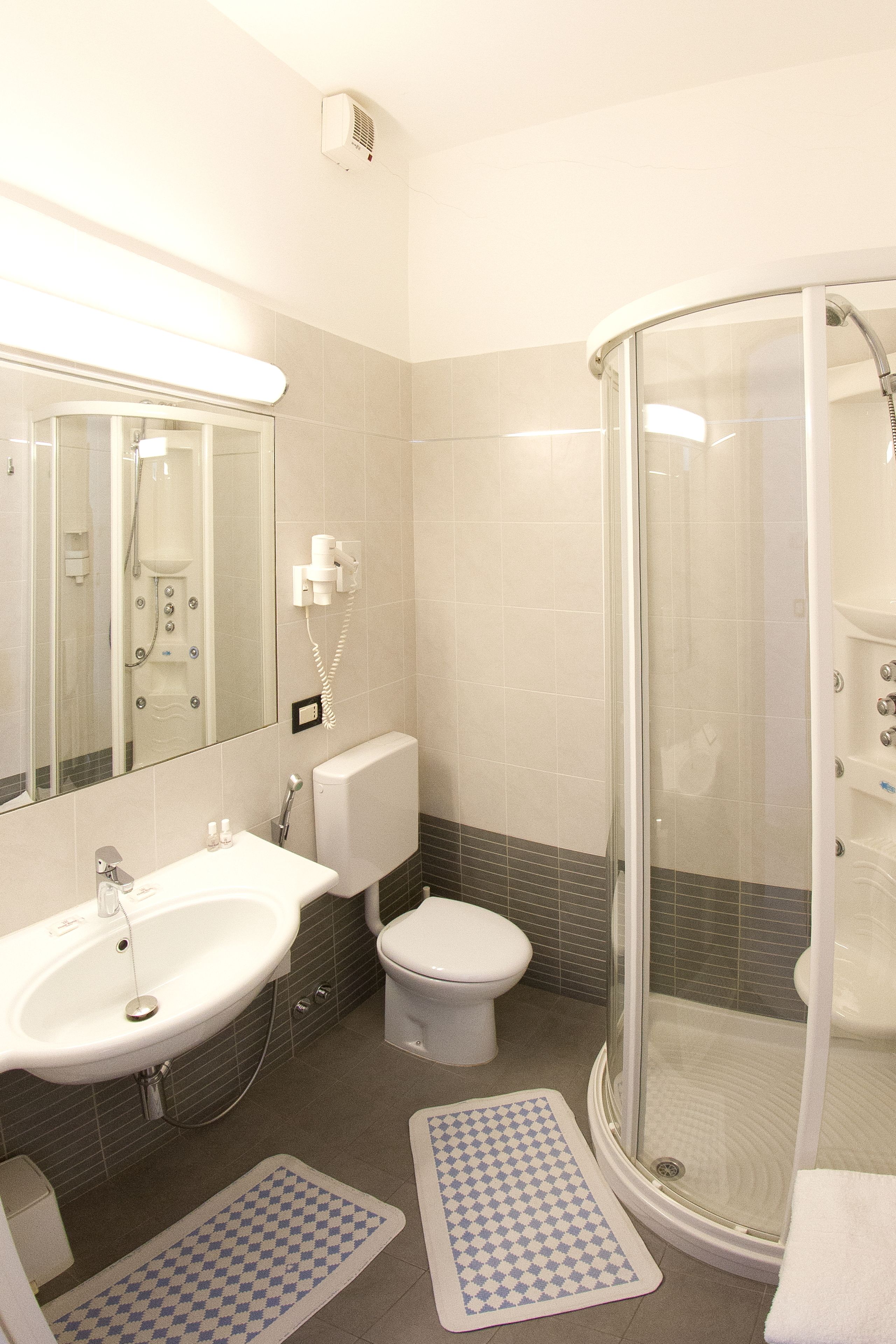 Ein modernes Badezimmer mit einer Duschkabine, einem weißen Waschbecken und einer Toilette.
