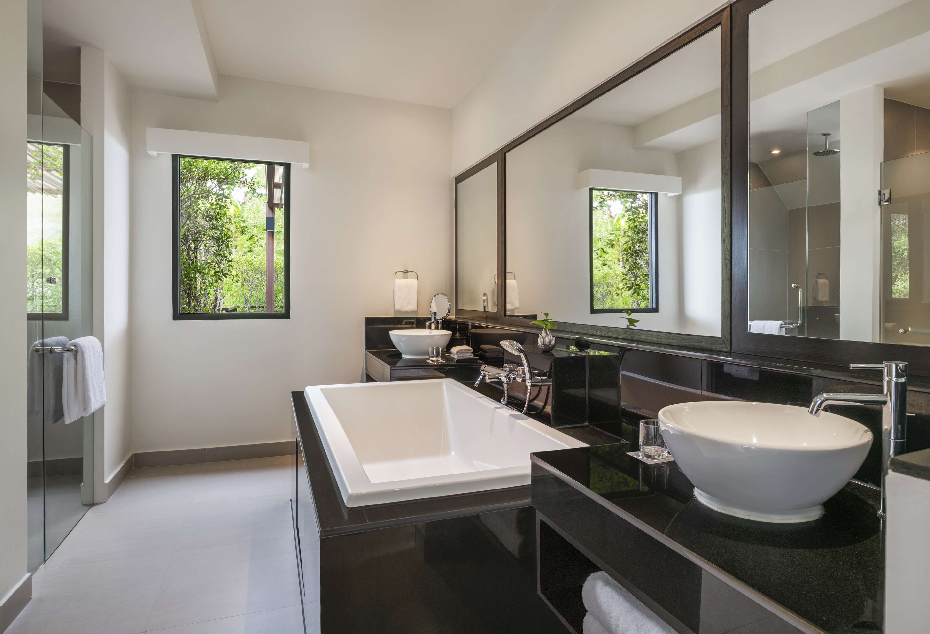 A modern bathroom with a large bathtub, a separate sink, and a large mirror.
