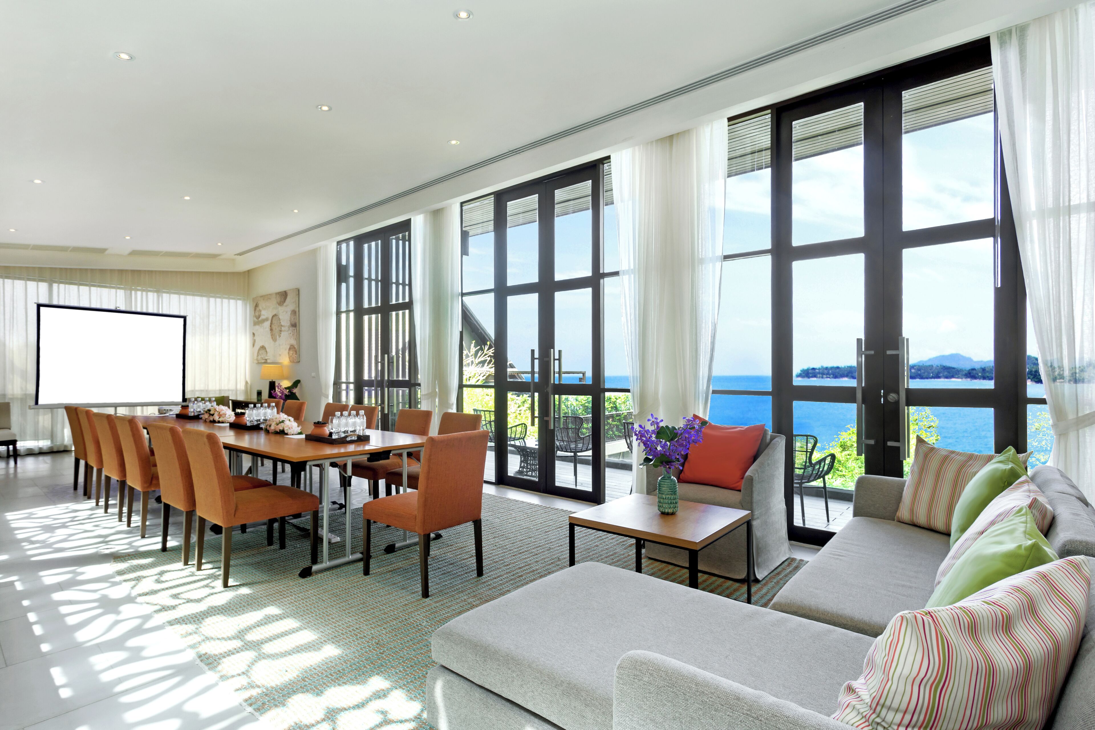 Una habitación amplia con un gran comedor, asientos cómodos y un sofá con vista al mar.
