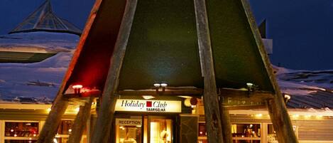 A hotel with a distinctive triangular roof structure and a reception area visible through the entrance.