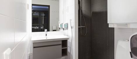 A modern bathroom with a white sink, mirror, and toilet.