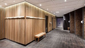 A modern, well-lit hallway with wooden paneling, a bench, and tiled flooring.