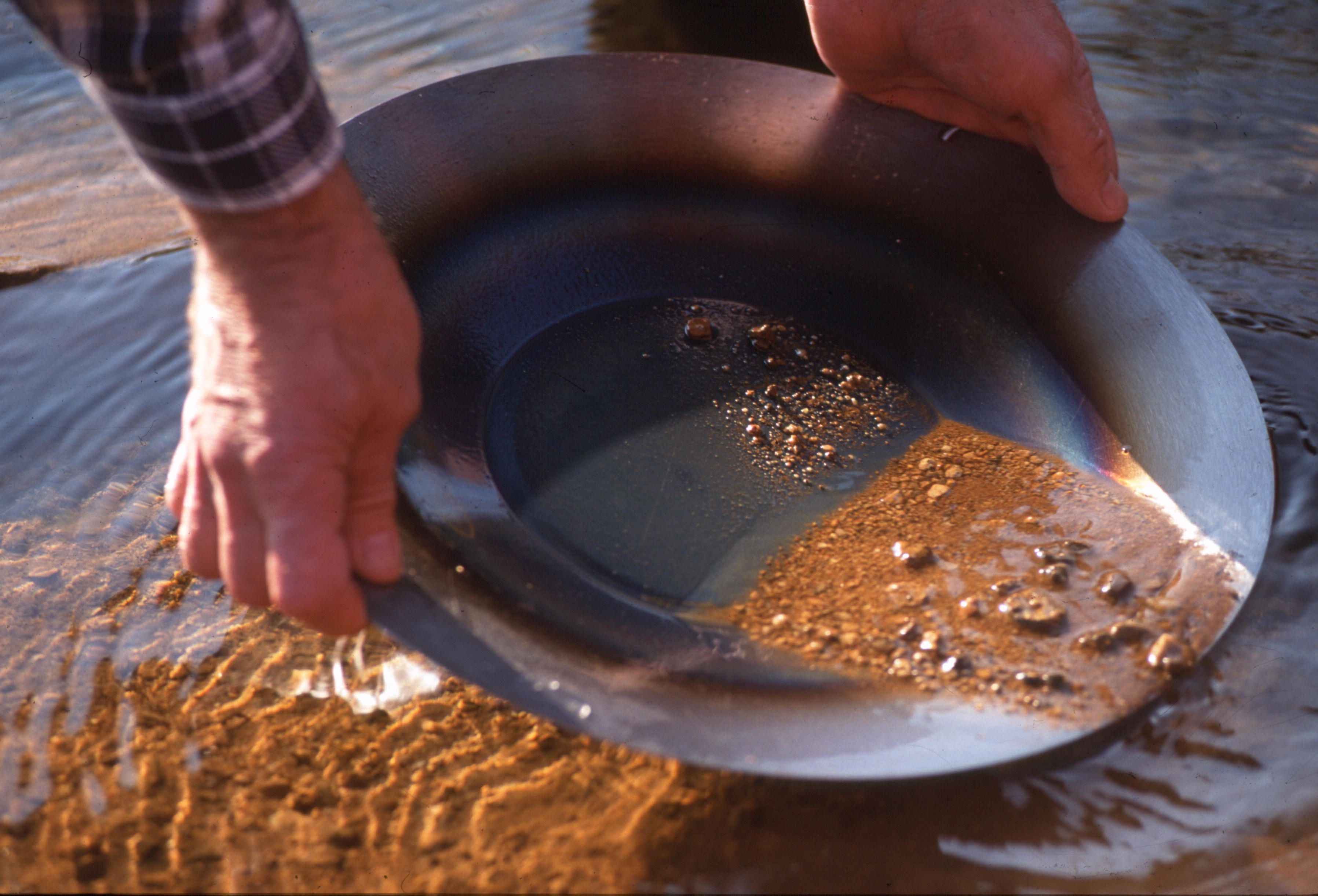 Iemand houdt een metalen kom boven water.