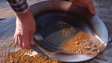 Iemand houdt een metalen kom boven water.