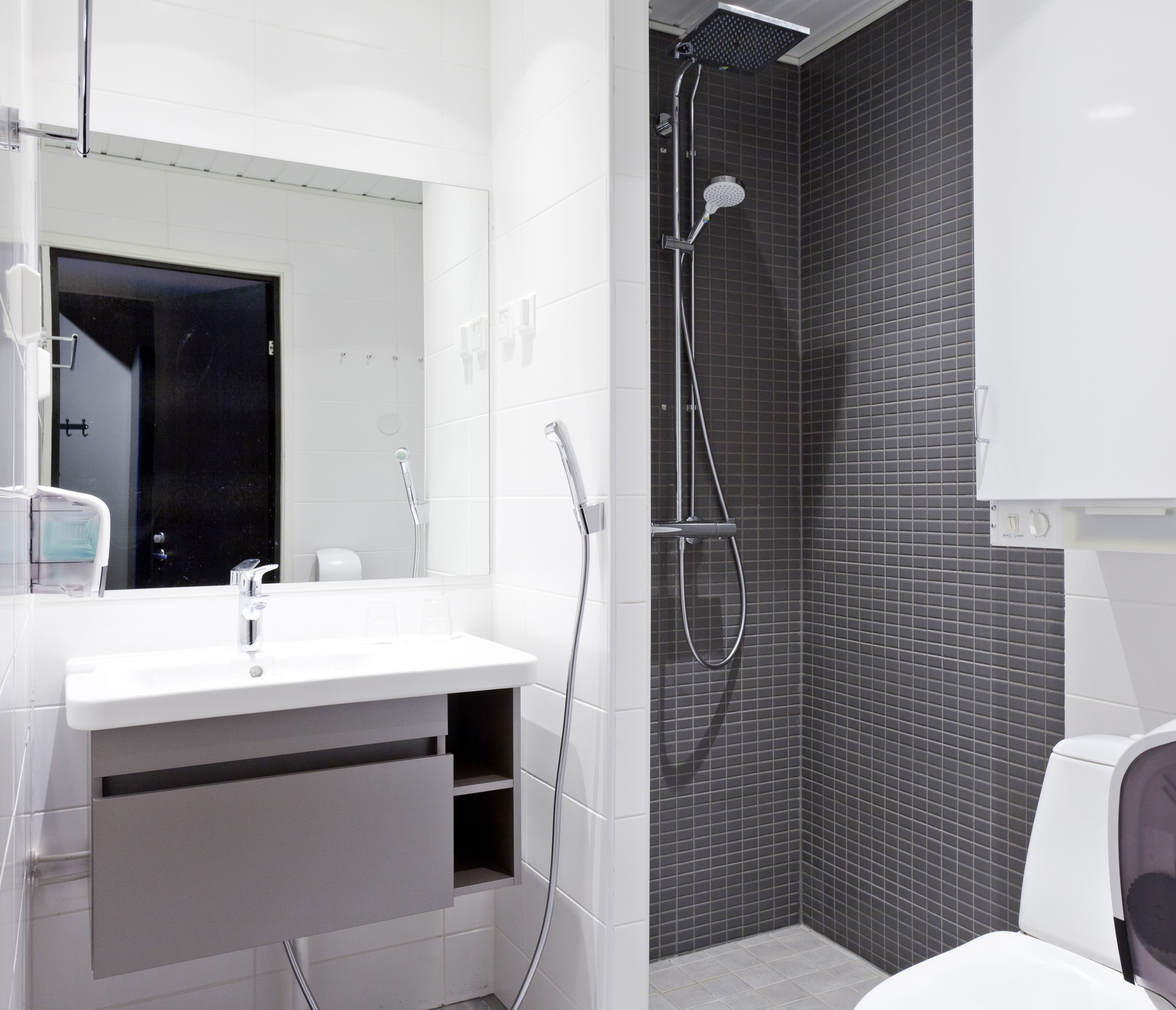 Une salle de bain moderne avec un lavabo blanc, un miroir et une douche.