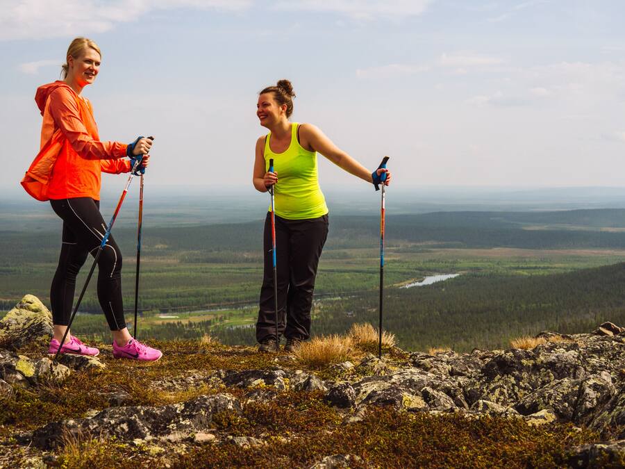 Two people hiking on a rocky terrain with a vast landscape in the background.