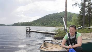 A lakeside setting with a dock, a rowboat, and a canoe.