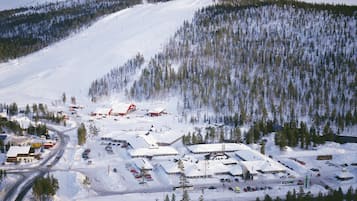 En snötäckt skidort med flera byggnader, vägar och parkerade fordon.