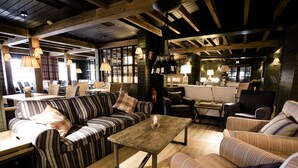 Un espace salon accueillant avec des canapés à rayures, une table basse en bois et des lampes suspendues.