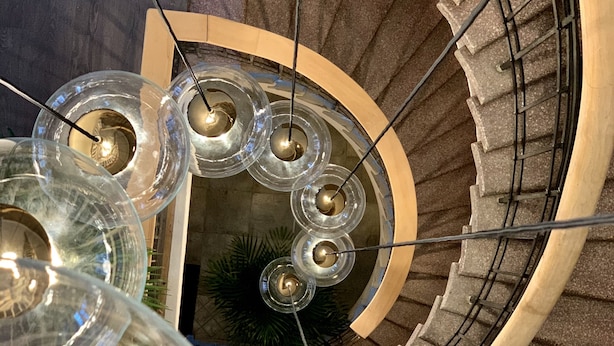 A spiral staircase with a circular railing and glass light fixtures. - Ludvika Stadshotell (Ludvika)