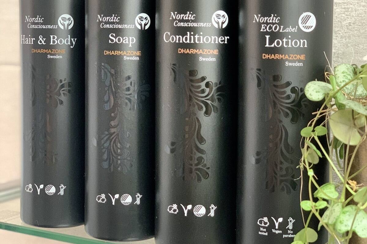 Quatre bouteilles noires de produits pour les cheveux et le corps de la marque Nordic Consciousness, disposées sur une étagère en verre.