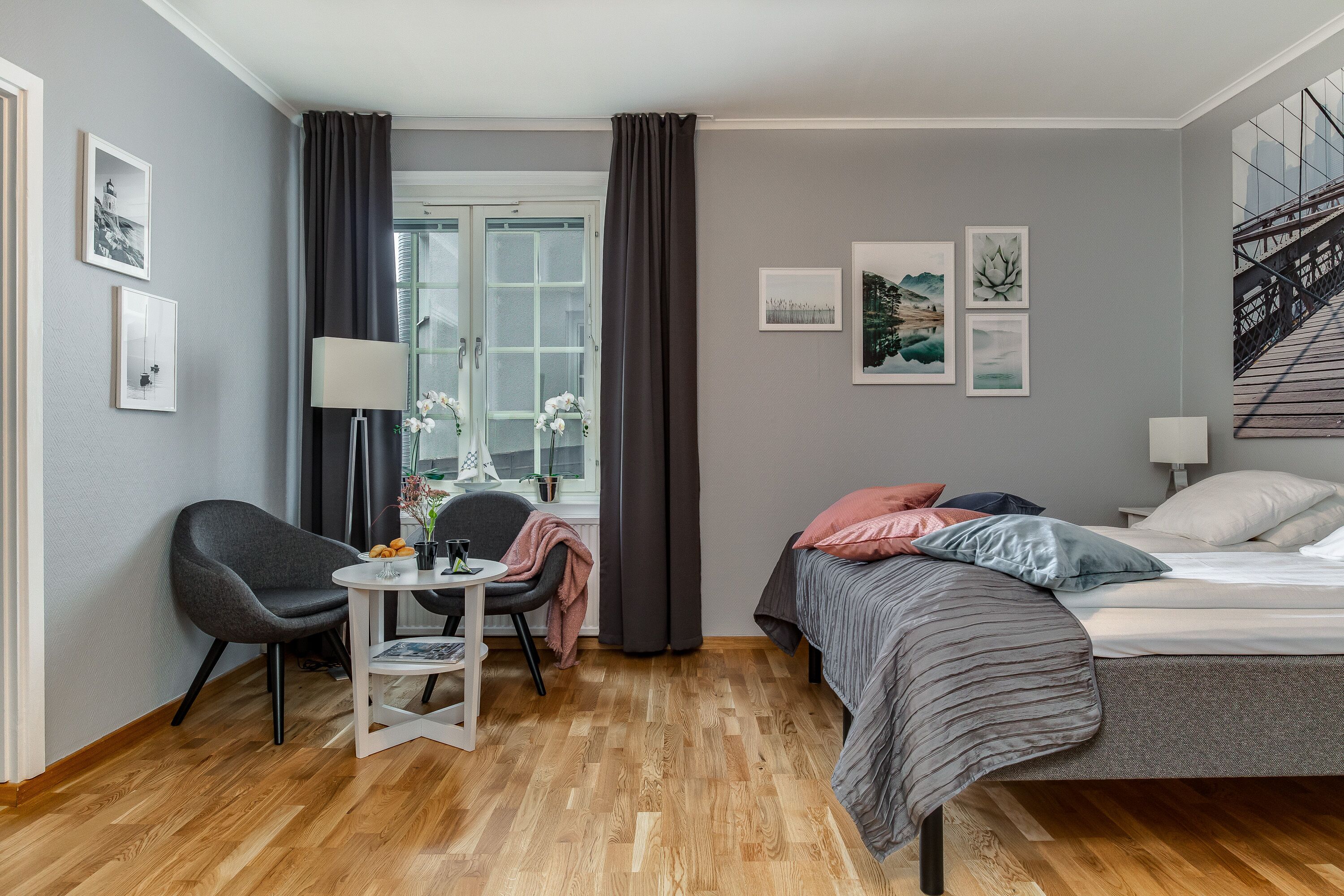 A modern bedroom with a bed, a desk, a chair, and a window with curtains.