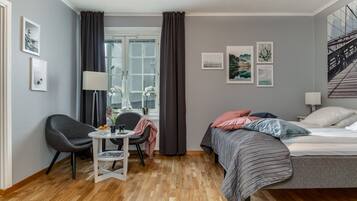 A modern bedroom with a bed, a desk, a chair, and a window with curtains.