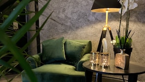 A cozy room with a green sofa, a round table with a lamp, and a potted plant. - Ludvika Stadshotell (Ludvika)