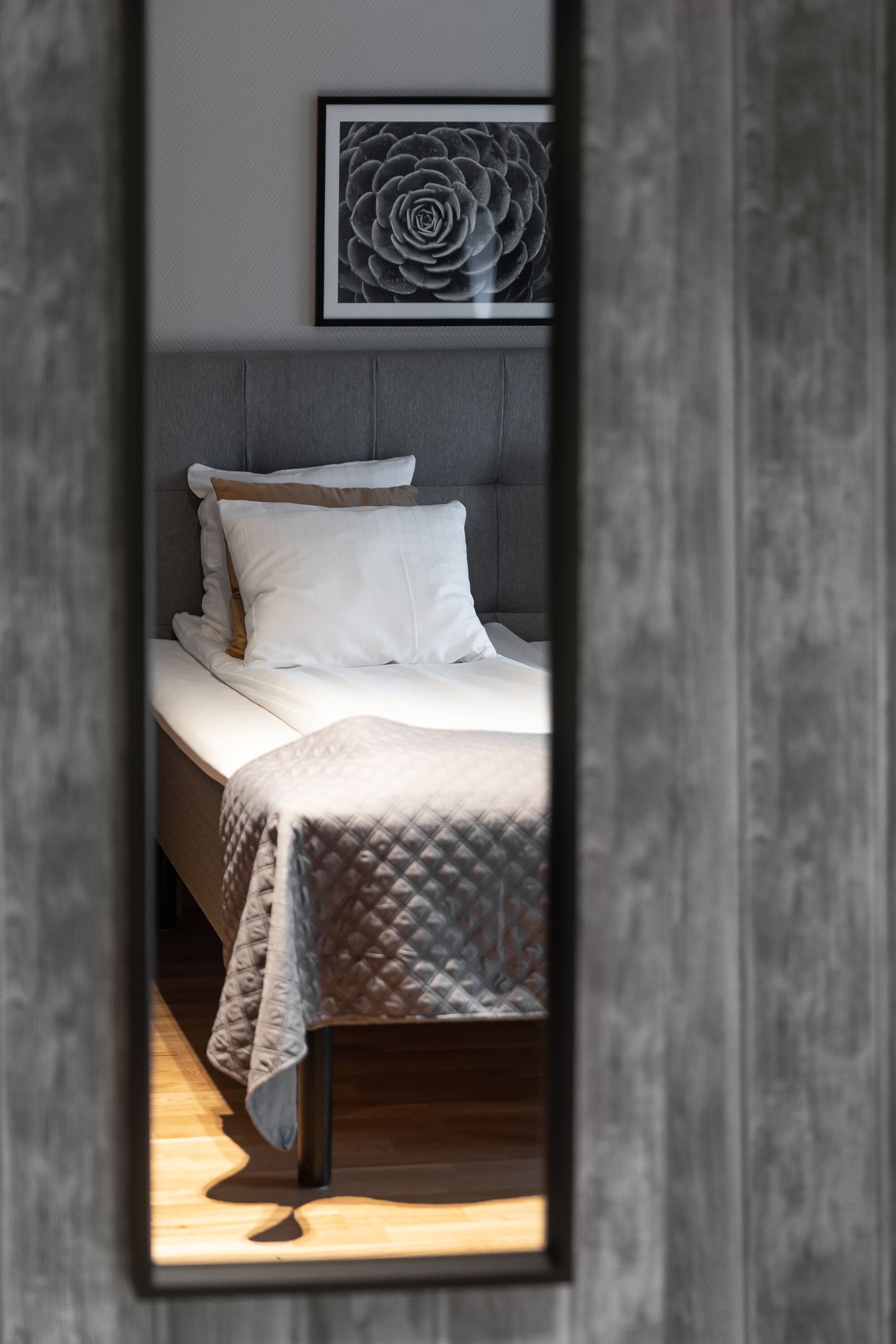 A modern bedroom with a bed, a headboard, and a framed artwork on the wall.