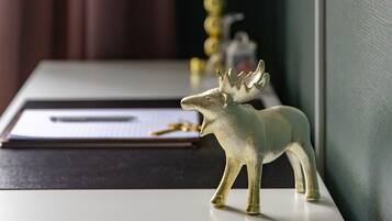 A desk with a moose figurine, a lamp, and a pen on a notepad.