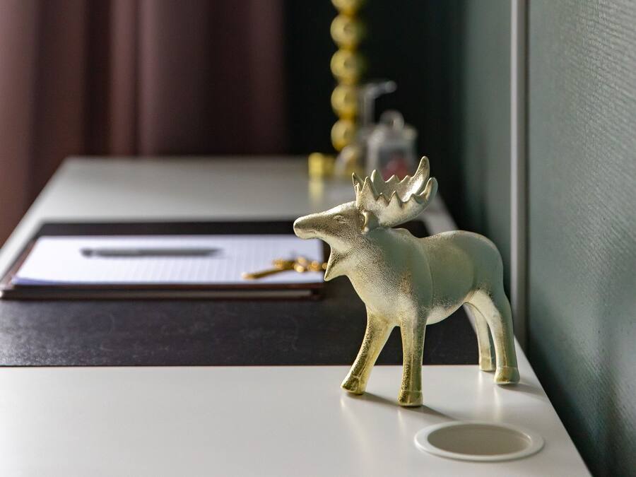 A desk with a moose figurine, a lamp, and a pen on a notepad.