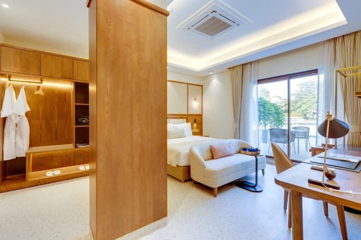 A hotel room with a bed, a sofa, a desk, and a wardrobe.