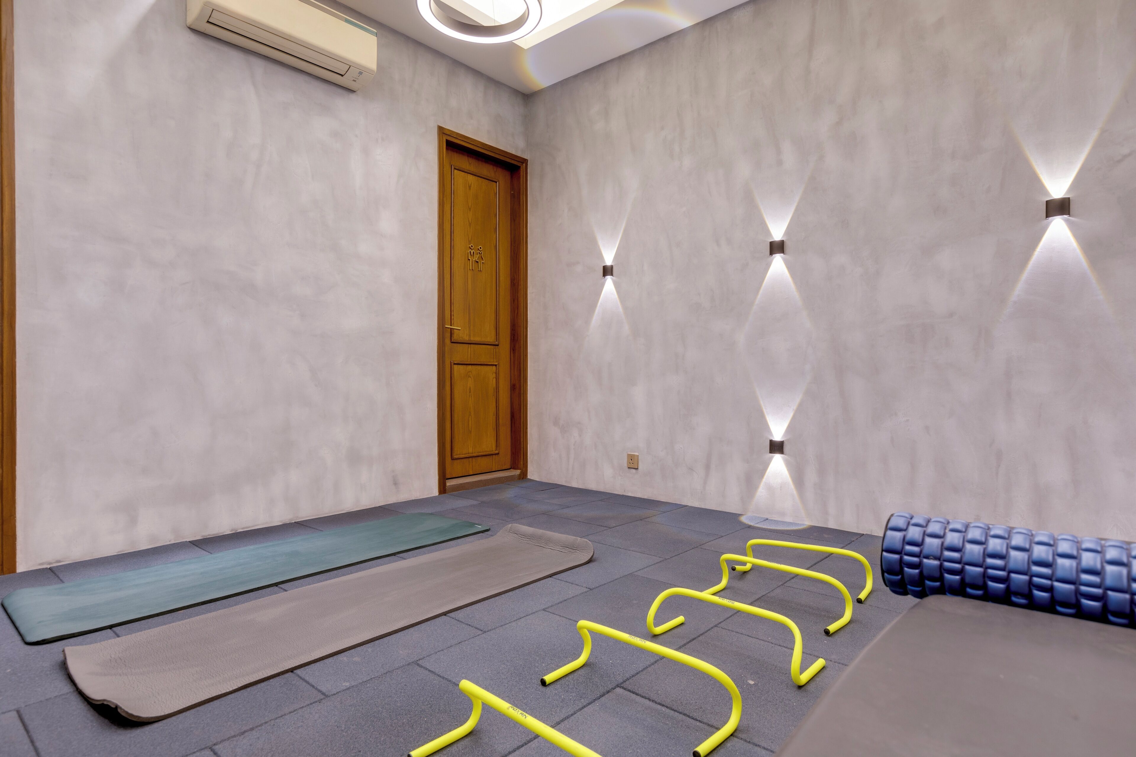A room with a wooden door, air conditioning unit, and exercise equipment including mats and resistance bands.