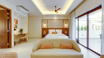 A modern hotel room with a large bed, a sofa, a desk, and a view of the outdoors.