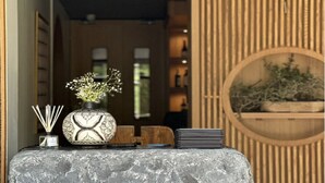 A reception desk with the name 'INJA' in gold letters, a vase with flowers, and a stack of black notebooks. - The Manor - New Delhi (New Delhi)