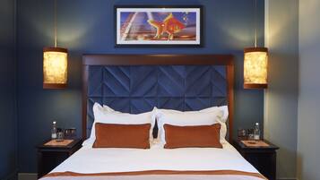 Habitación de hotel con una cama grande, dos mesitas de noche, una obra de arte enmarcada sobre la cama y dos lámparas de pared.