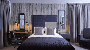 A modern hotel room with a large bed, a desk, and a chair.