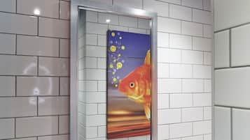 A framed artwork of a goldfish with bubbles on a white tiled wall.