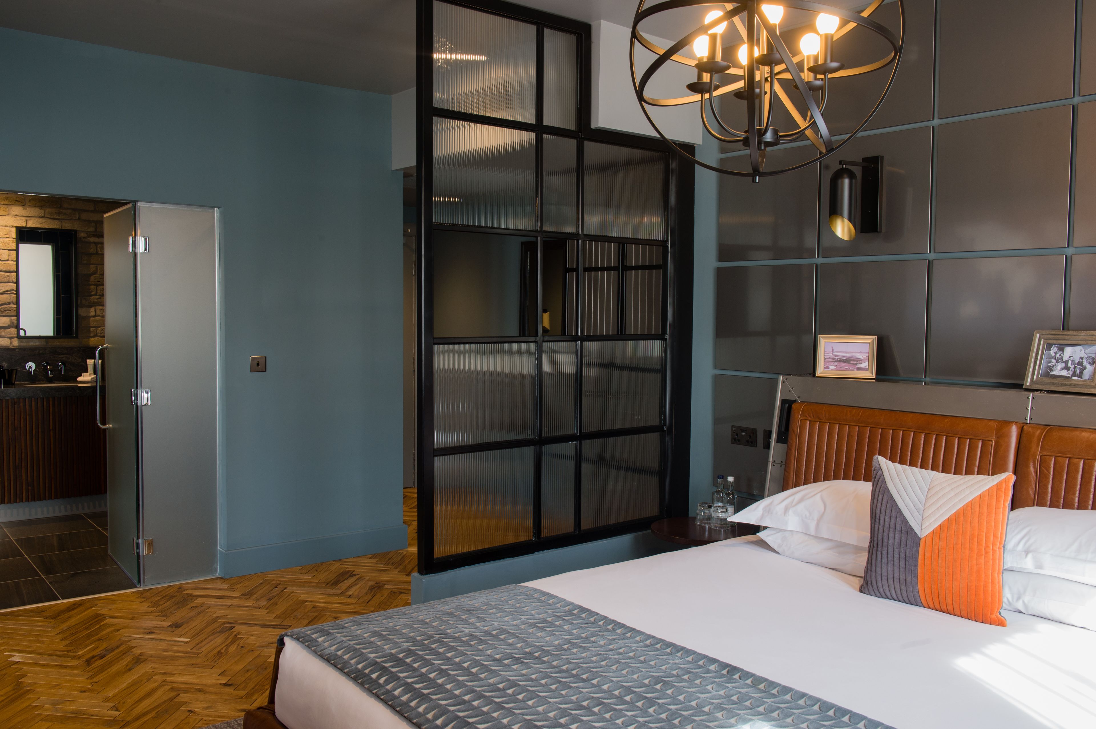 A modern hotel room with a large bed, a separate bathroom, a built-in wardrobe, and a unique wall design.