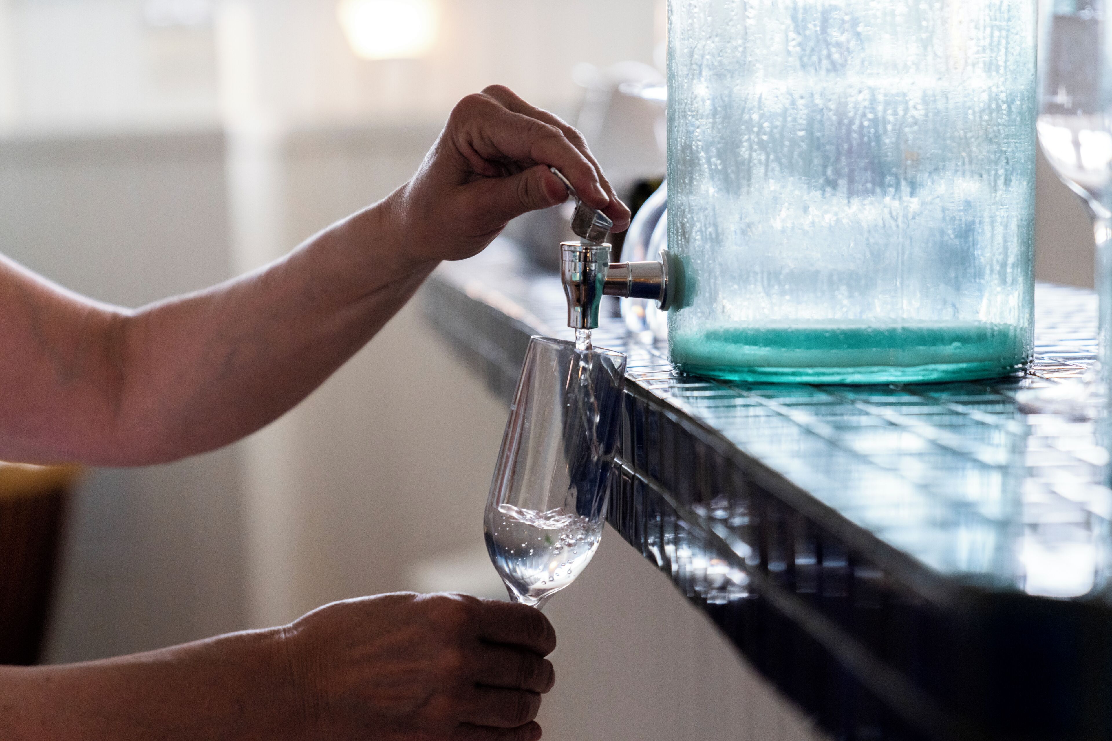 A hand filling a glass from a tap.