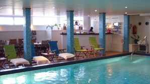 A pool area with lounge chairs and a bar.