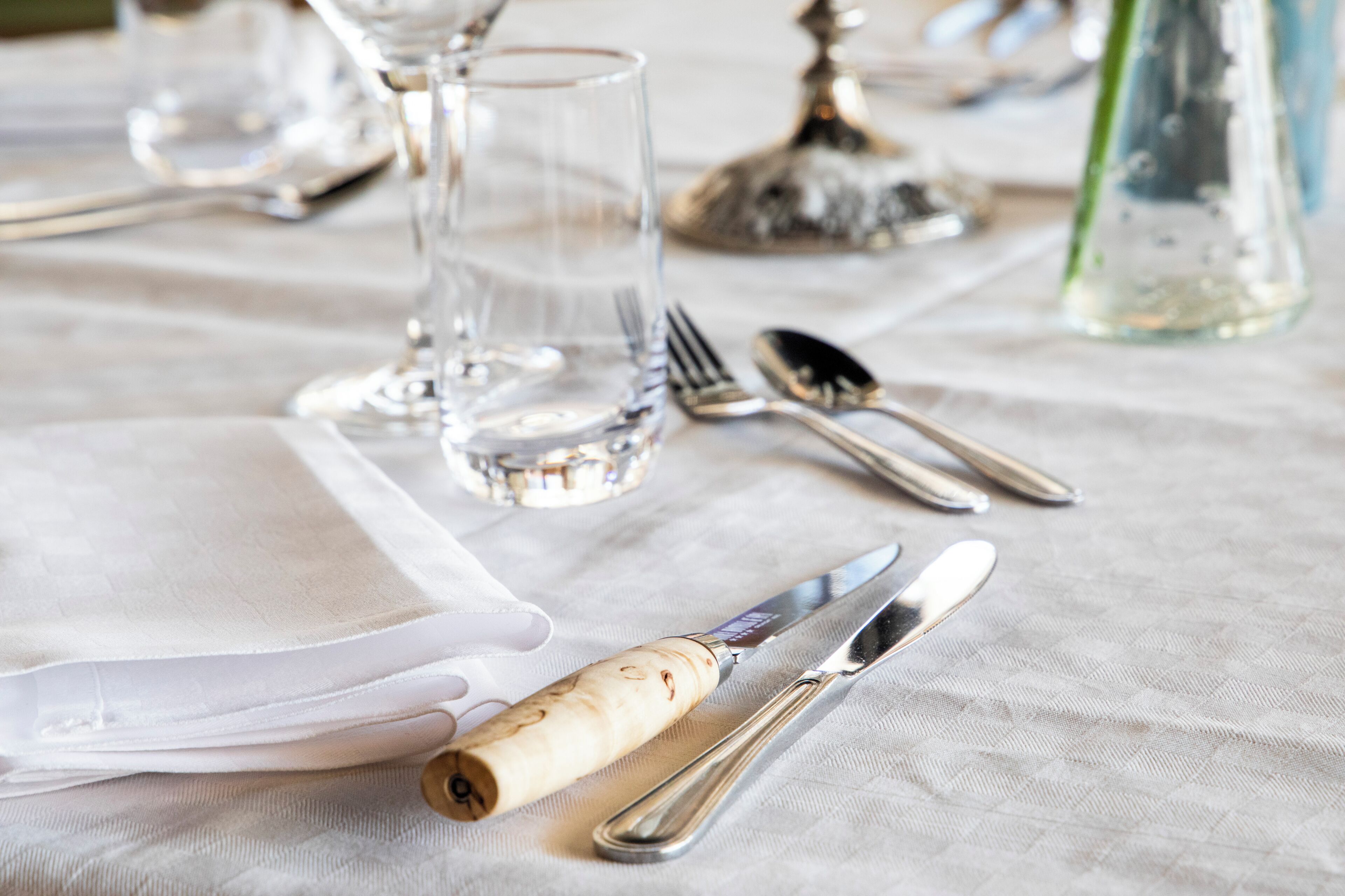 A table set with cutlery, a glass, and a napkin.
