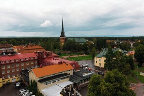 A hotel with a red roof, a church with a tall spire, and a green park in the background.