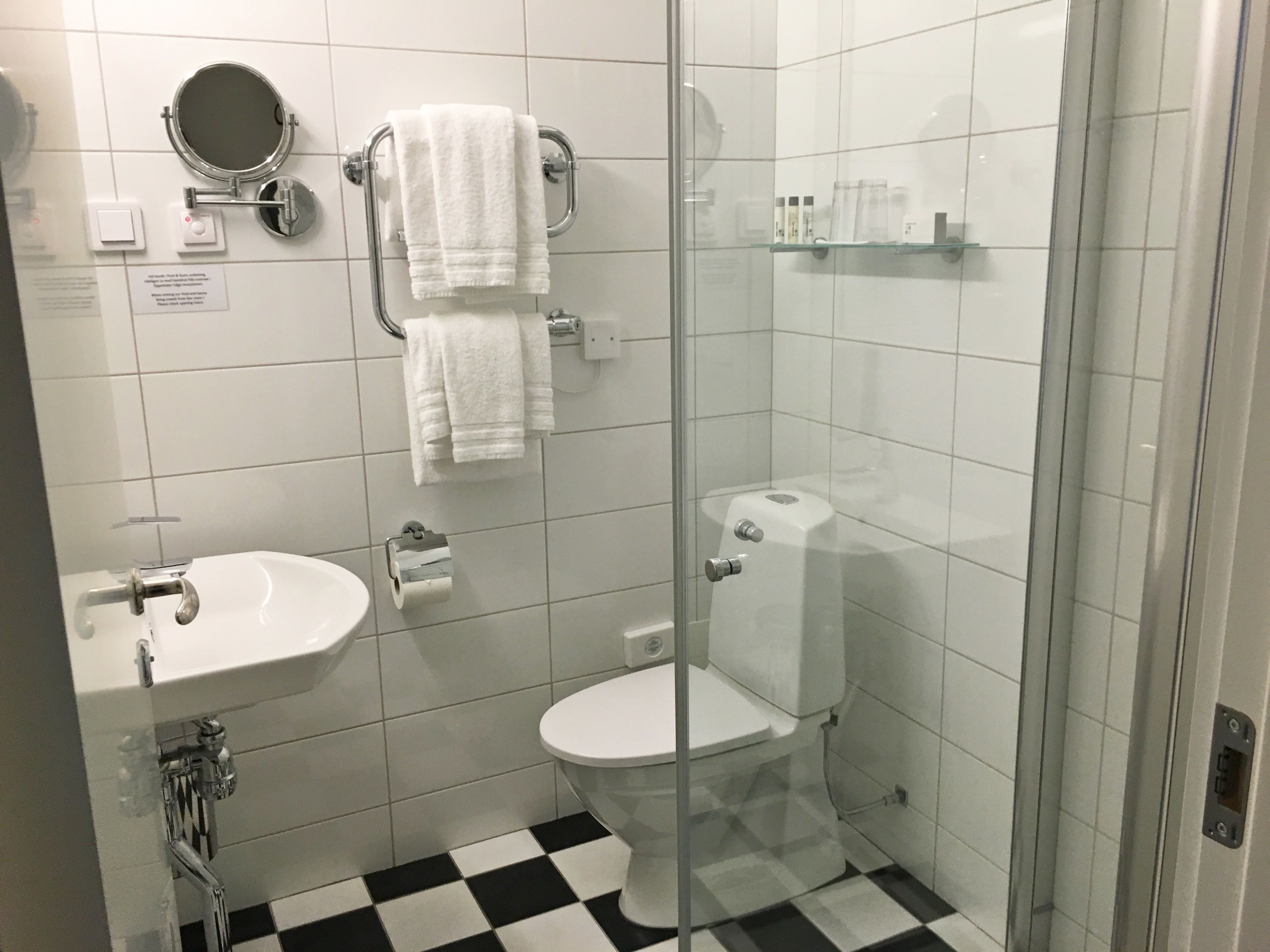A bathroom with a white sink, toilet, and a glass-enclosed shower area.