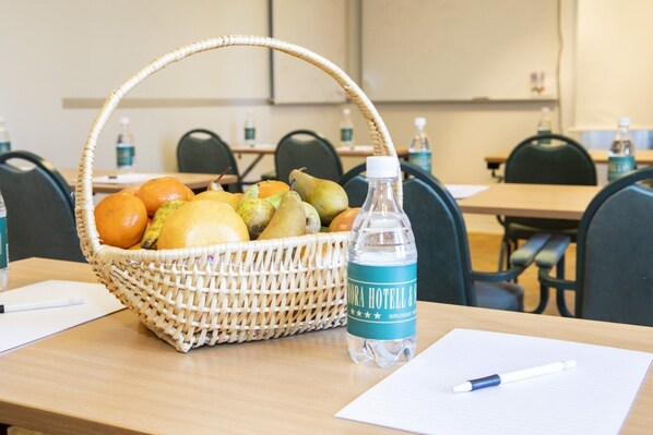 A conference room with a wicker fruit basket, a bottle of water, and a notepad on a table.