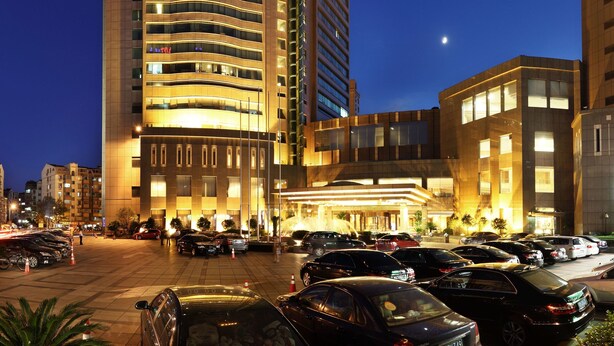 A high-rise hotel with a curved facade, multiple balconies, and a well-lit entrance area. - Ningbo Nanyuan Hotel (Ningbo)