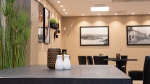 Un espace repas comprenant une table, des chaises et un mur décoré de tableaux encadrés.