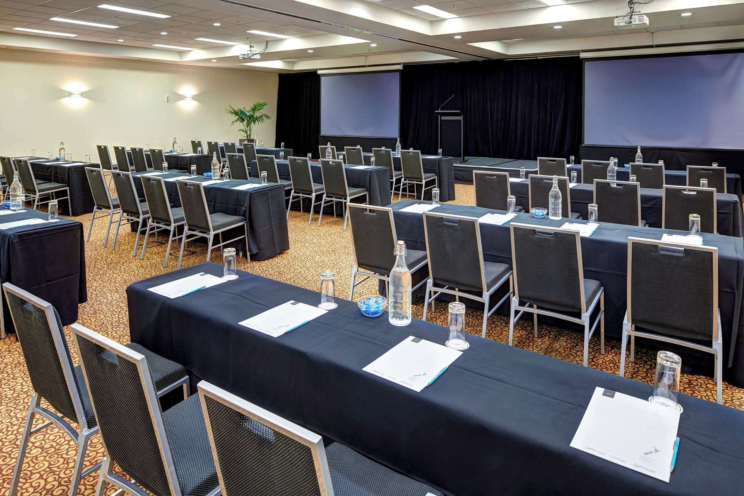 A conference room with rows of tables and chairs, equipped with water bottles and nameplates.
