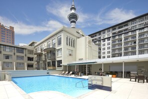 Un hotel con piscina, mobiliario exterior y vistas a una torre.