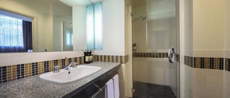 A bathroom with a double sink, a glass shower enclosure, and a large mirror.