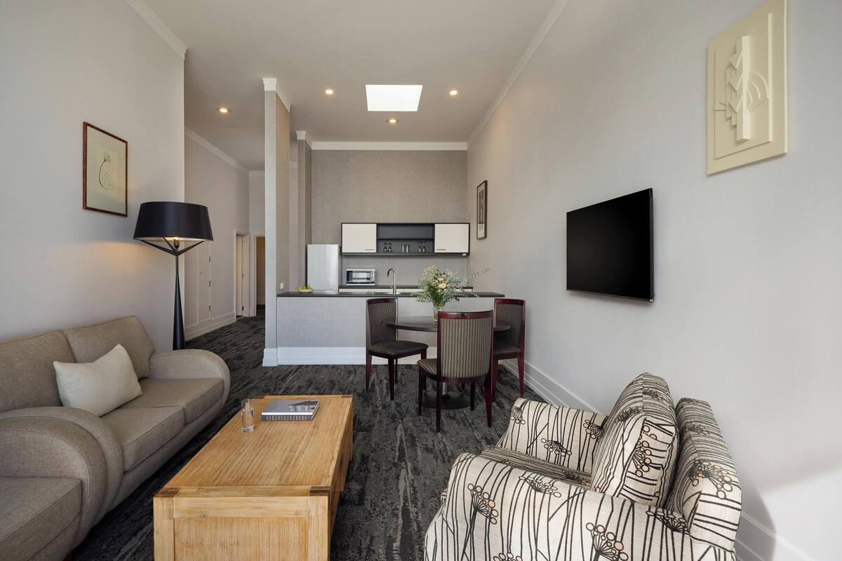 A modern living room with a sofa, coffee table, and a dining area with chairs and a table.