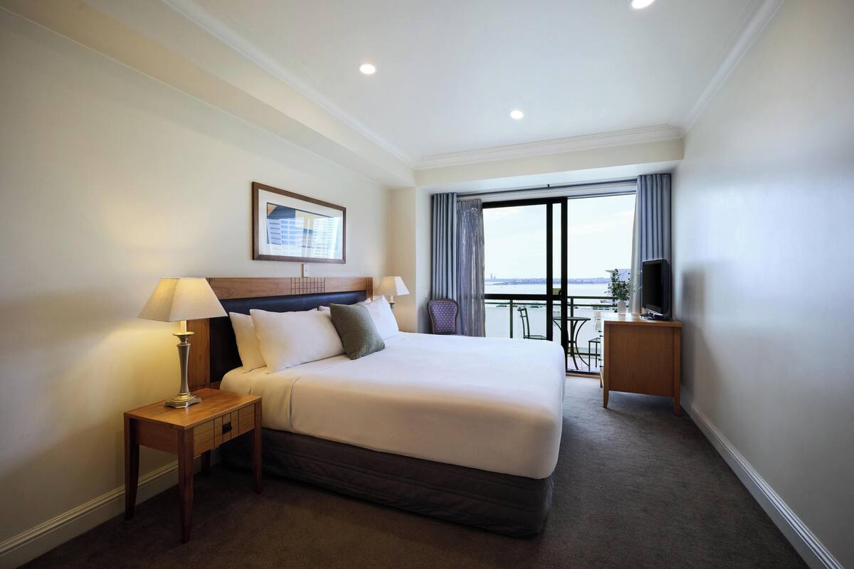 Une chambre d’hôtel avec un grand lit, deux tables de chevet, une télévision et un balcon avec vue.