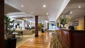 Un vestíbulo de hotel con recepción, zona de estar y una planta grande.