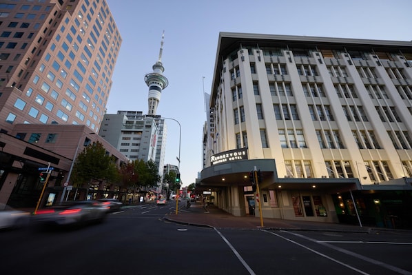 A hotel with a prominent sign, a street view, and a tower in the background.
