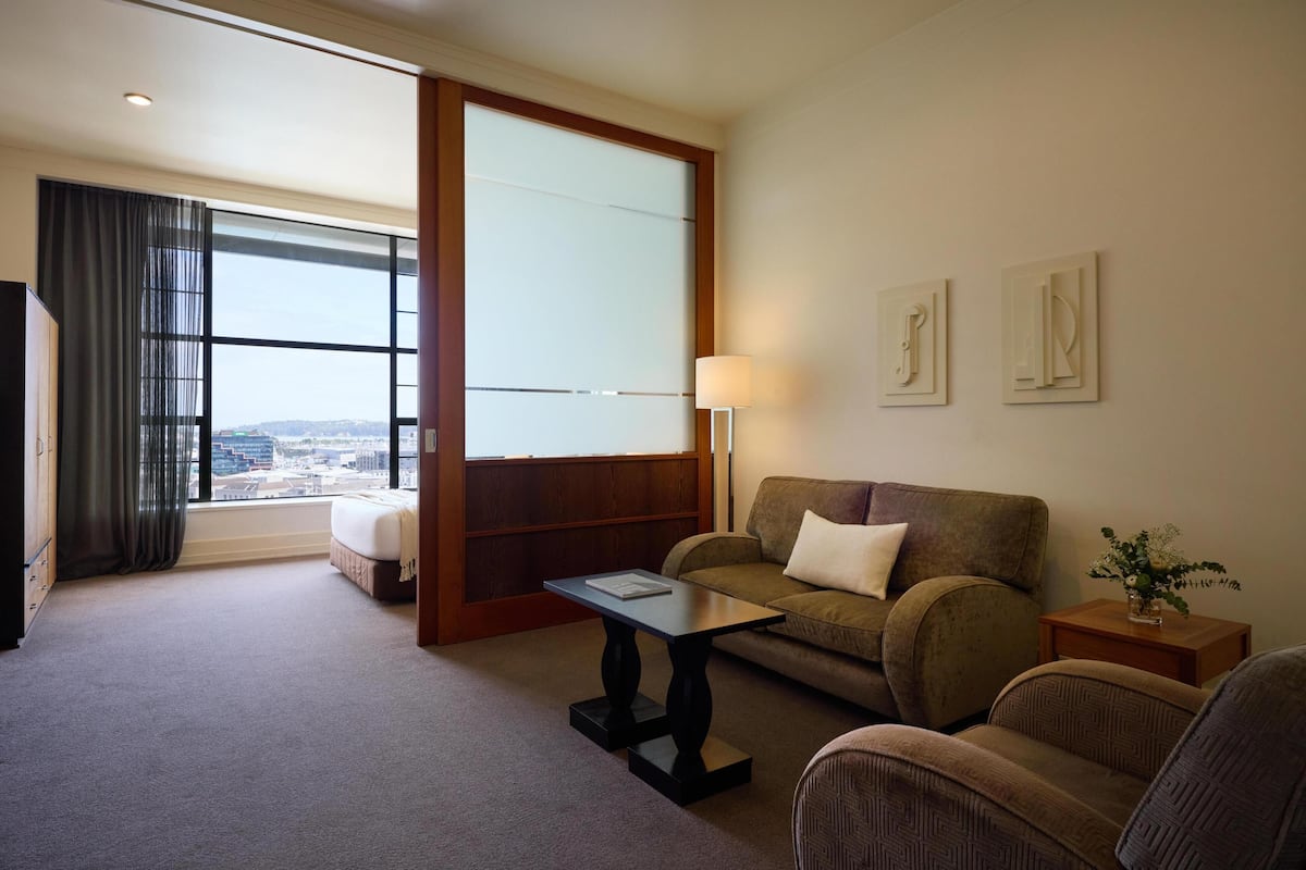 Une chambre d’hôtel avec une grande fenêtre, un canapé, une petite table et une lampe.