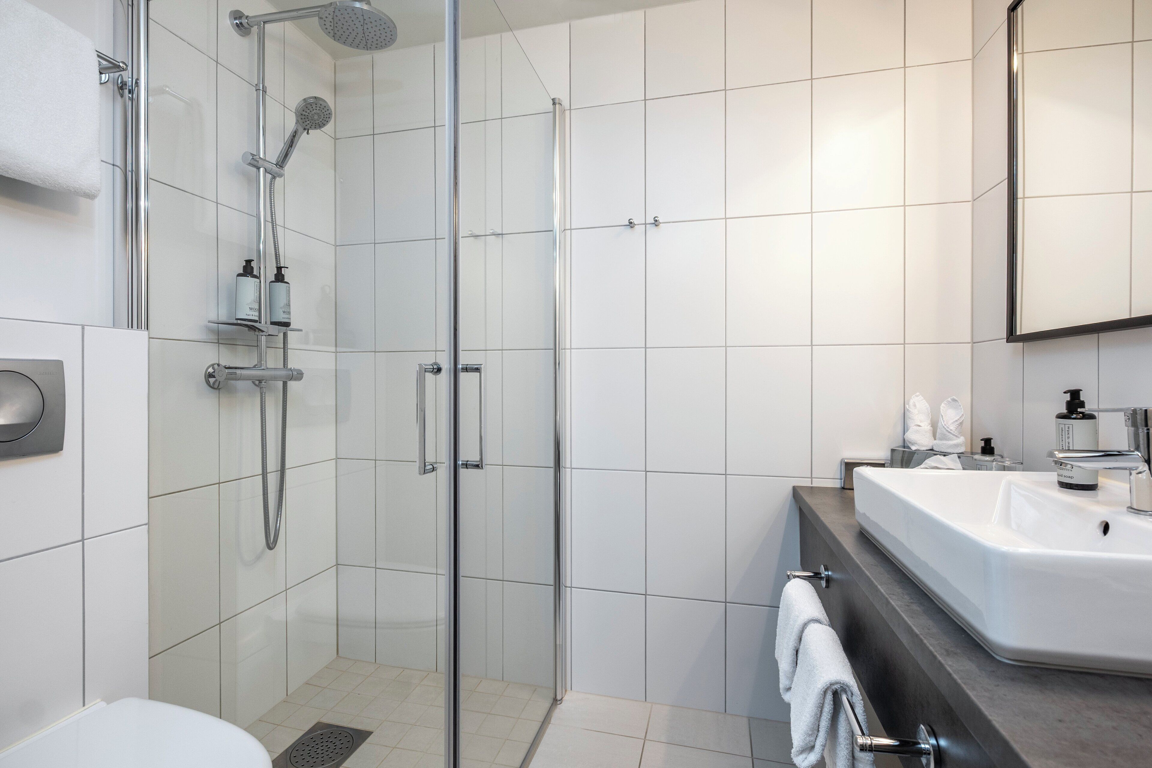 Un bagno moderno con doccia vetro, lavabo sospeso e water.