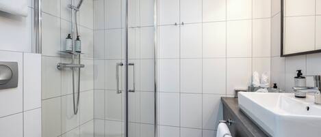 A modern bathroom with a glass-enclosed shower, a standalone sink, and a toilet.