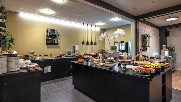 A buffet area with various food items and a decorative plant. - Thon Hotel Baronen (Ålesund)