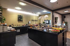 A buffet area with various food items and a decorative plant. - Thon Hotel Baronen (Ålesund)